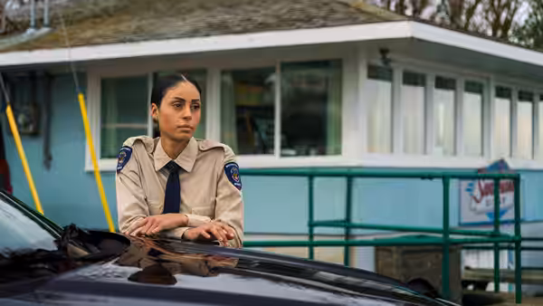 A woman in uniform leaning on the hood of a car