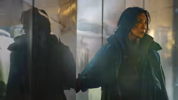Olwen (Michelle Yeoh) standing with hand on glass in a foggy corridor