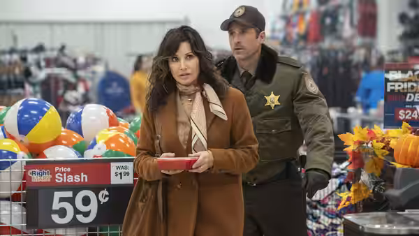 A woman carries a red tray through a store with a sheriff behind her