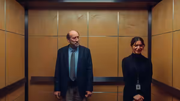Paul Matthews (Nicolas Cage) standing in an elevator next to a smiling woman