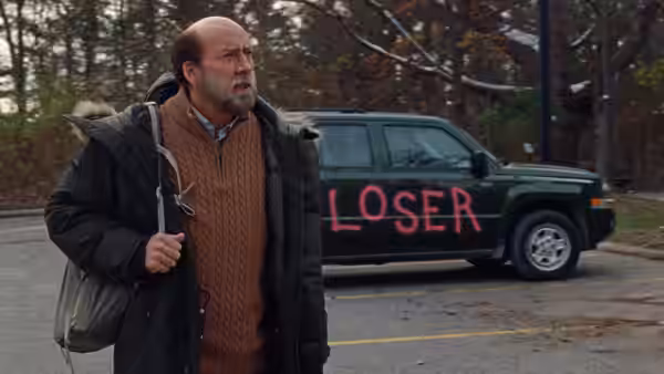 Paul Matthews (Nicolas Cage) carrying a bag past a car marked LOSER