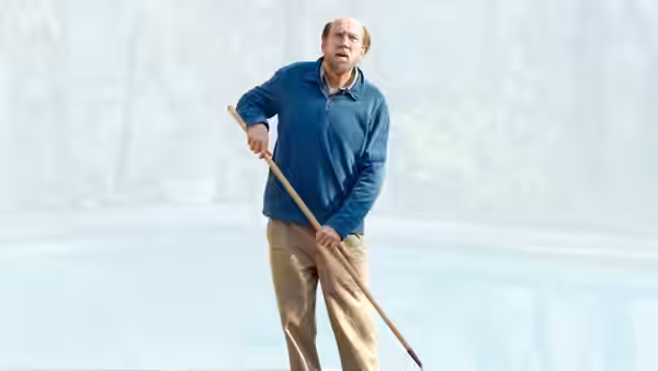 Paul Matthews (Nicolas Cage) holding a pool skimmer beside a swimming pool