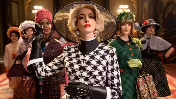 Grand High Witch (Anne Hathaway) gesturing among witches in a grand hall