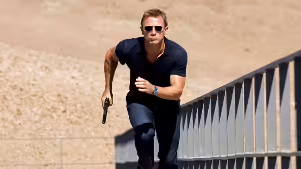 James Bond (Daniel Craig) running along a structure holding a handgun