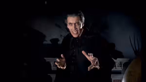 Count Dracula (Christopher Lee) bares his fangs and reaches forward in a dark room