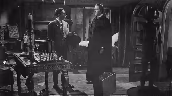 Doctor Van Helsing (Peter Cushing) stands with a man beside laboratory equipment