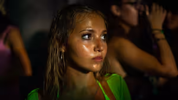 Sweaty woman in green top looking upwards in a crowded club