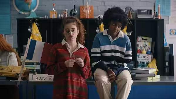PJ (Rachel Sennott) holding a French flag beside Josie (Ayo Edebiri) in class