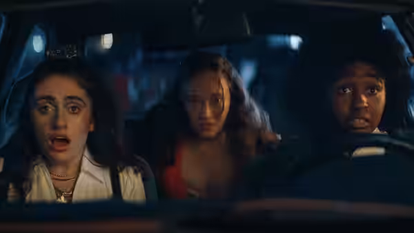 PJ (Rachel Sennott) wearing a tiara in a car with two others at night