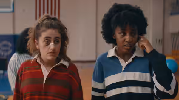 PJ (Rachel Sennott) and Josie (Ayo Edebiri) standing together in a gymnasium