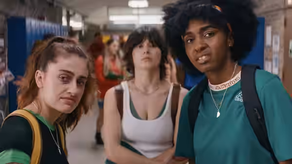 Josie (Ayo Edebiri) in a green shirt walking through a school hallway
