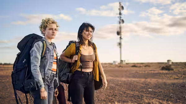Hanna (Julia Garner) and Liv (Jessica Henwick) walking through a remote desert landscape