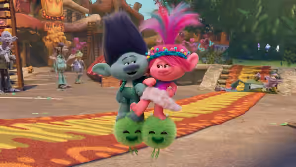 Poppy (Anna Kendrick) and Branch (Justin Timberlake) held aloft by two small green trolls on a path