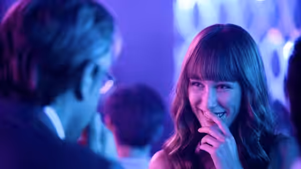 Liliana (Almudena Amor) smiling at a man in a blue-lit bar