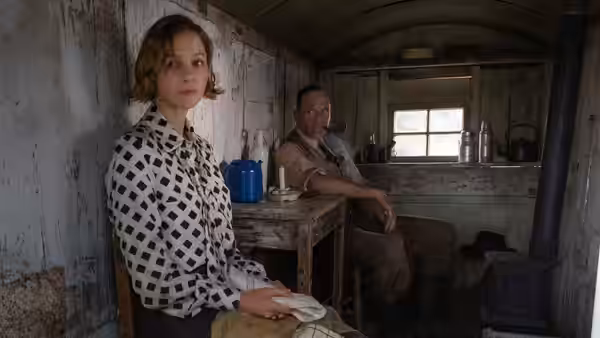 Edith Pretty (Carey Mulligan) sits at a table inside a wooden hut