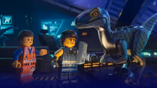 Two minifigures with a velociraptor in a dimly lit control room