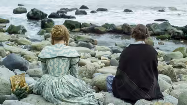 Charlotte Murchison (Saoirse Ronan) and Mary Anning (Kate Winslet) sit among rocks beside the sea