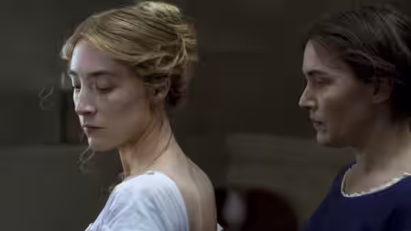 Charlotte Murchison (Saoirse Ronan) stands before Mary Anning (Kate Winslet) in a dim room