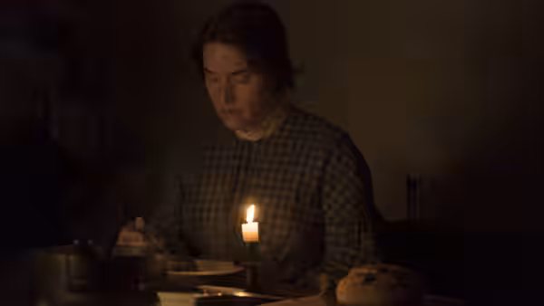 Mary Anning (Kate Winslet) sits at a table beside a lit candle