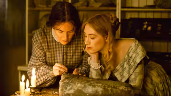 Mary Anning (Kate Winslet) and Charlotte Murchison (Saoirse Ronan) examine a fossil by candlelight