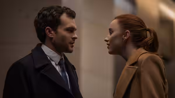 Luke (Alden Ehrenreich) and Emily (Phoebe Dynevor) facing each other in a hallway