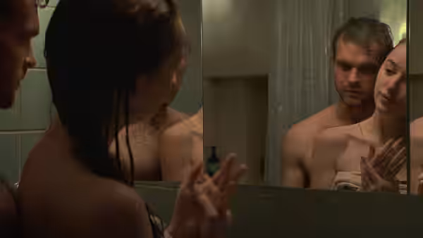 Luke (Alden Ehrenreich) and Emily (Phoebe Dynevor) reflected in a bathroom mirror