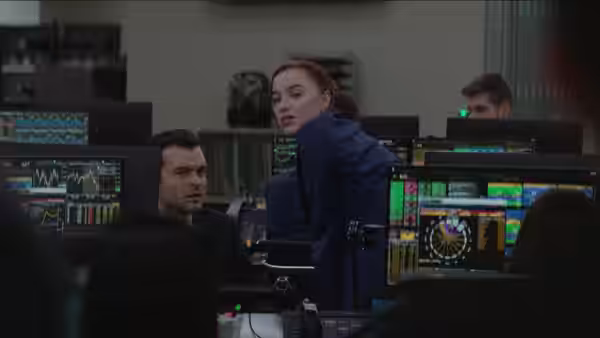 Emily (Phoebe Dynevor) turning toward Luke (Alden Ehrenreich) at trading desks