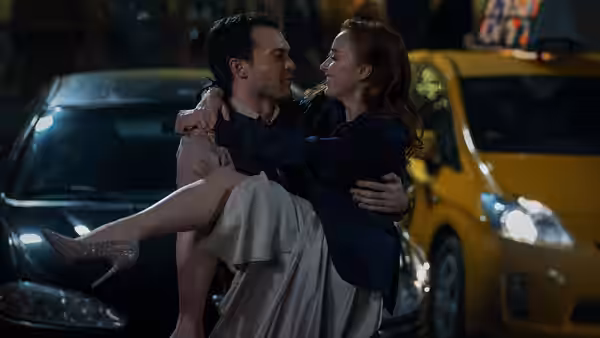 Luke (Alden Ehrenreich) lifting Emily (Phoebe Dynevor) on a city street at night