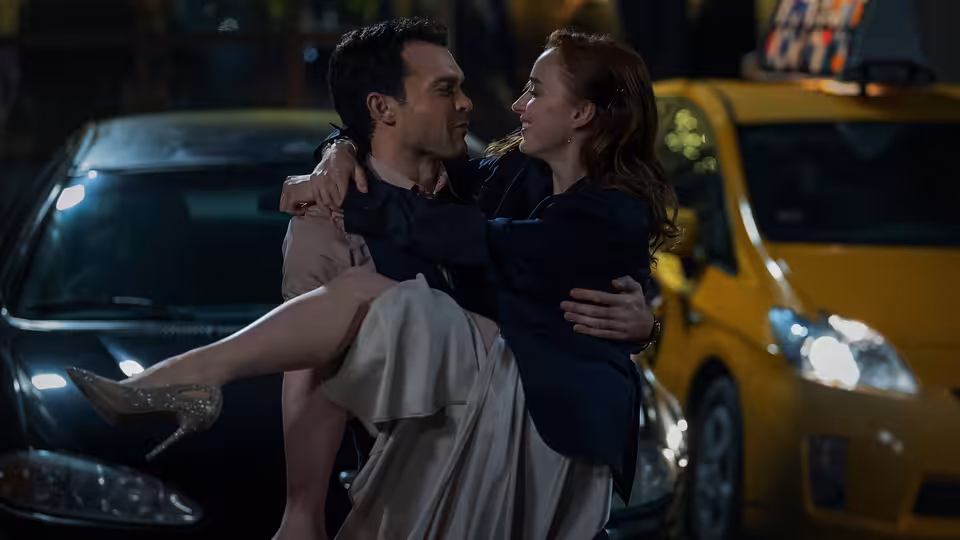 Luke (Alden Ehrenreich) lifting Emily (Phoebe Dynevor) on a city street at night