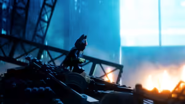 Batman crouches on a metal structure beside a raging fire