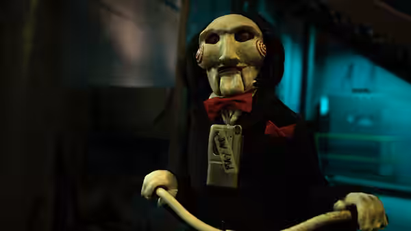 a puppet in a suit and red bow tie gripping tricycle handles