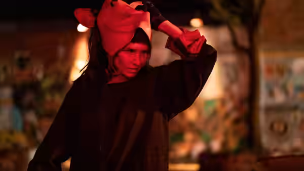a woman in a pink pig costume adjusting her hood outdoors