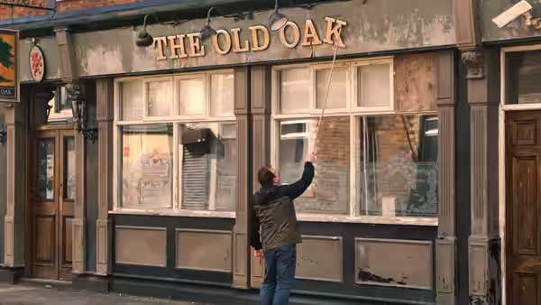 Man reaches up to clean the windows of The Old Oak