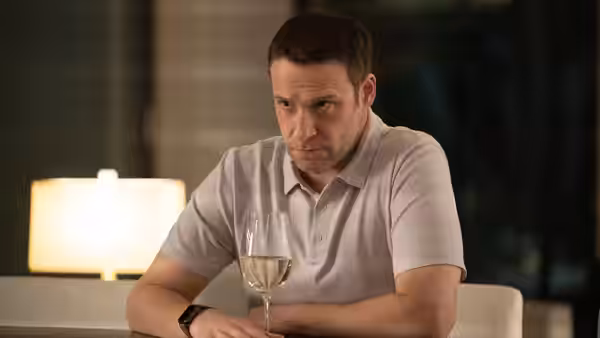 man in a polo shirt staring at a glass of white wine