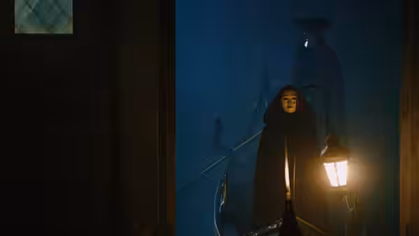 Woman in hooded cloak holding a lantern on a gondola at night
