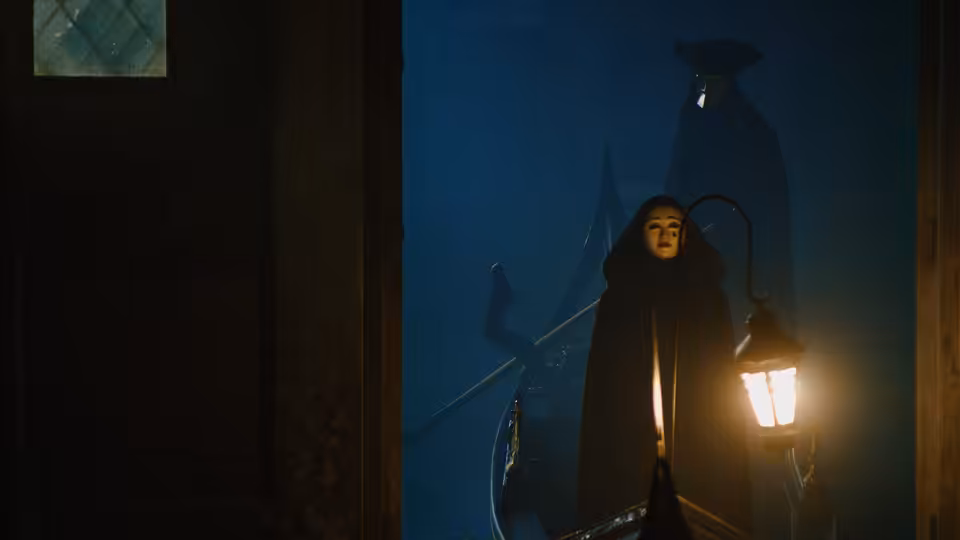 Woman in hooded cloak holding a lantern on a gondola at night