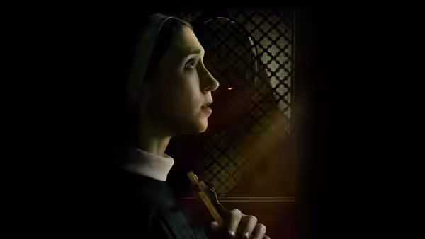 Sister Irene (Taissa Farmiga) holding a crucifix beside a latticed window