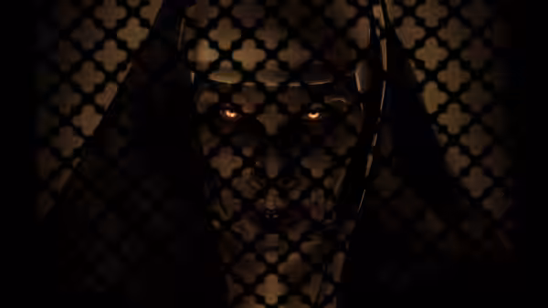 The Demon Nun (Bonnie Aarons) with glowing eyes behind a metal grate