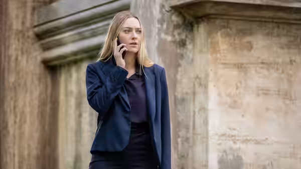 Emma Collins (Dakota Fanning) talking on a phone outside a stone building