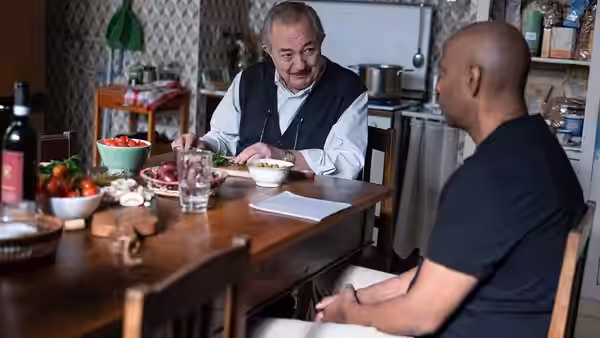 Enzo Arisio (Remo Girone) eating with Robert McCall (Denzel Washington) at a kitchen table