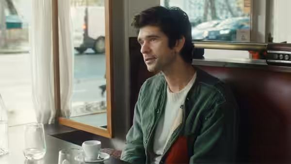 Ben Whishaw as Martin seated in a cafe booth looking out the window