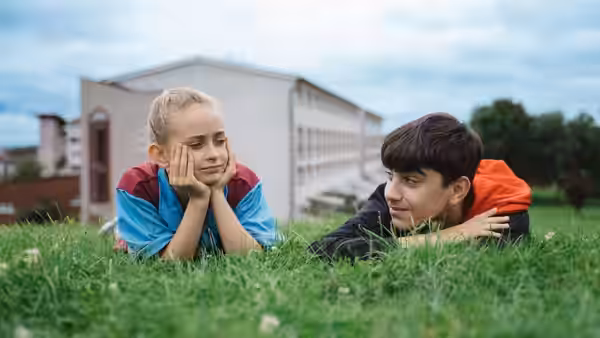 Georgie (Lola Campbell) and a boy lying on grass looking at each other