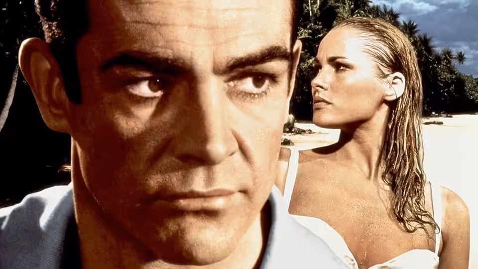 James Bond (Sean Connery) in close-up with Honey Ryder (Ursula Andress) behind