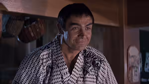 James Bond (Sean Connery) wearing a patterned robe in a wooden room