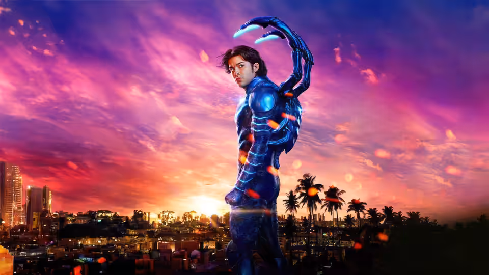 Jaime Reyes (Xolo Maridueña) in Blue Beetle armor overlooking a city at sunset