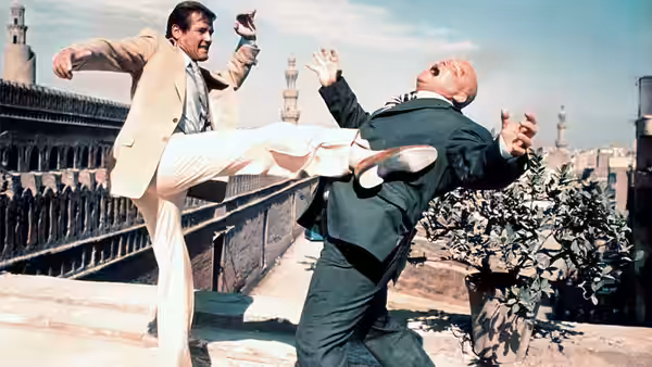James Bond (Roger Moore) kicking a bald man during a rooftop fight