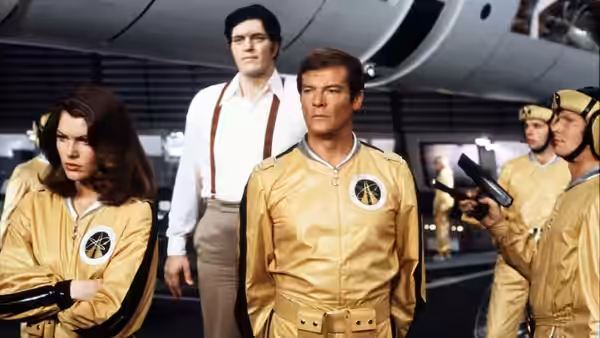 James Bond (Roger Moore) stands with Holly Goodhead (Lois Chiles) among yellow-suited workers aboard a spacecraft