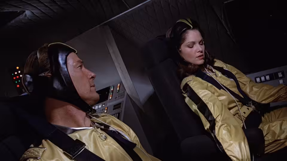 James Bond (Roger Moore) and Holly Goodhead (Lois Chiles) sit strapped into spacecraft seats