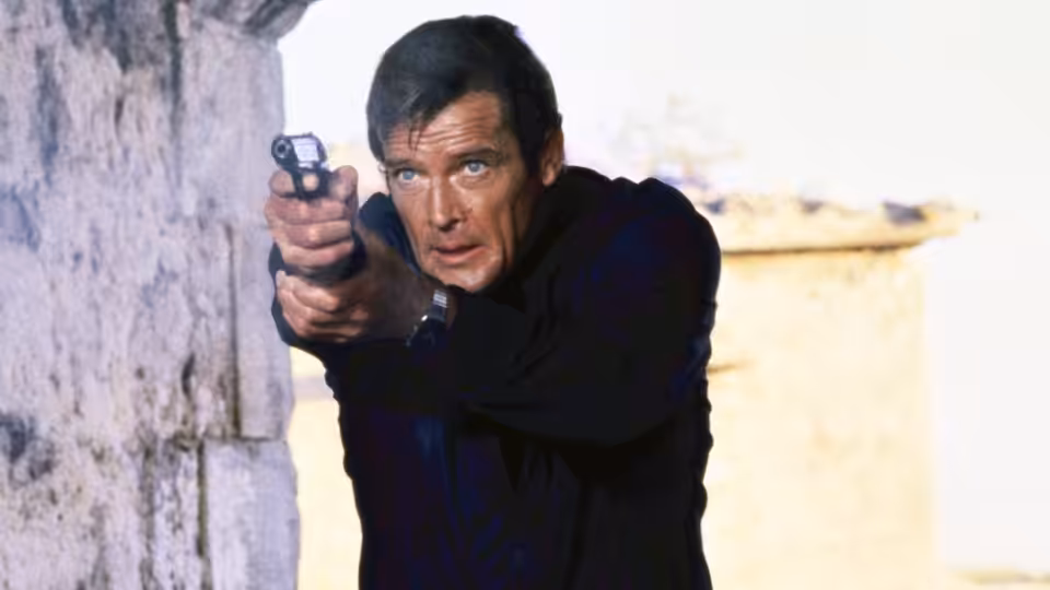 James Bond (Roger Moore) aiming a pistol near a weathered stone wall