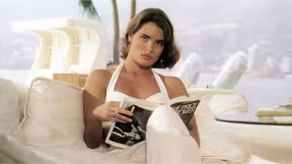 Woman in white halter top reclining on outdoor sofa reading a magazine
